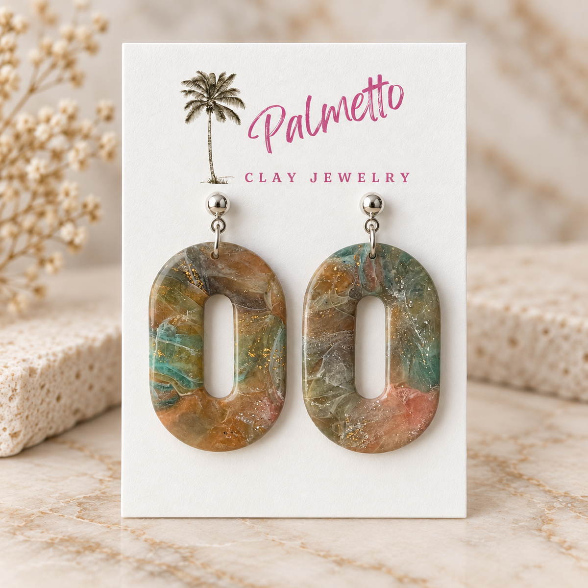 Open oval marbled polymer clay earrings in muted teal, tan, blush, cream, and gold fleck tones with silver-tone posts.