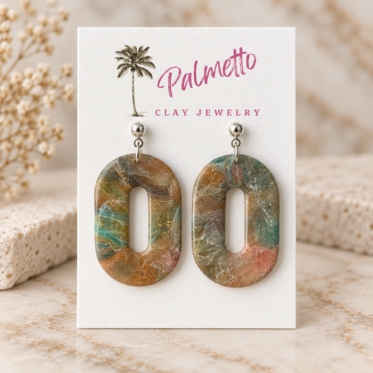 Open oval marbled polymer clay earrings in muted teal, tan, blush, cream, and gold fleck tones with silver-tone posts.