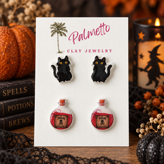 Two-pair Halloween stud earring set with black cat earrings and red poison potion bottle earrings on a Palmetto Clay Jewelry card.